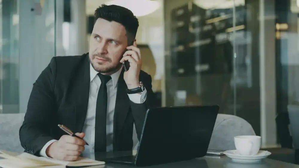 A man on a serious phone call at his desk