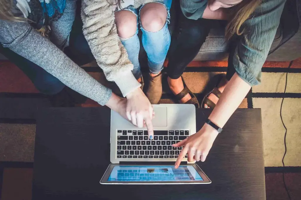 photo of many people pointing at a macbook screen seeing the data on an article about real estate advertising law content